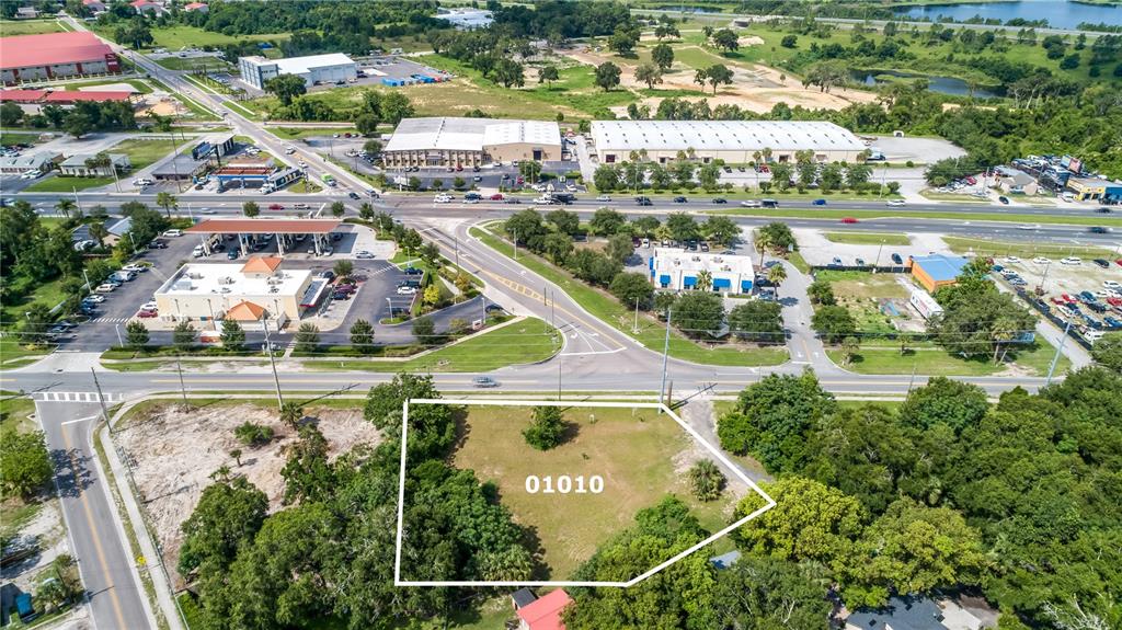 An aerial view shows a vacant, grass-covered lot outlined in white near a commercial area — 449 OLD DIXIE HIGHWAY, APOPKA, FL