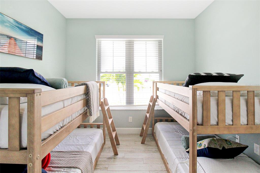 A bedroom features two wooden bunk beds with light-colored flooring and a central window — 14550 SCHOFIELD ROAD UNIT 3, PORT CHARLOTTE, FL