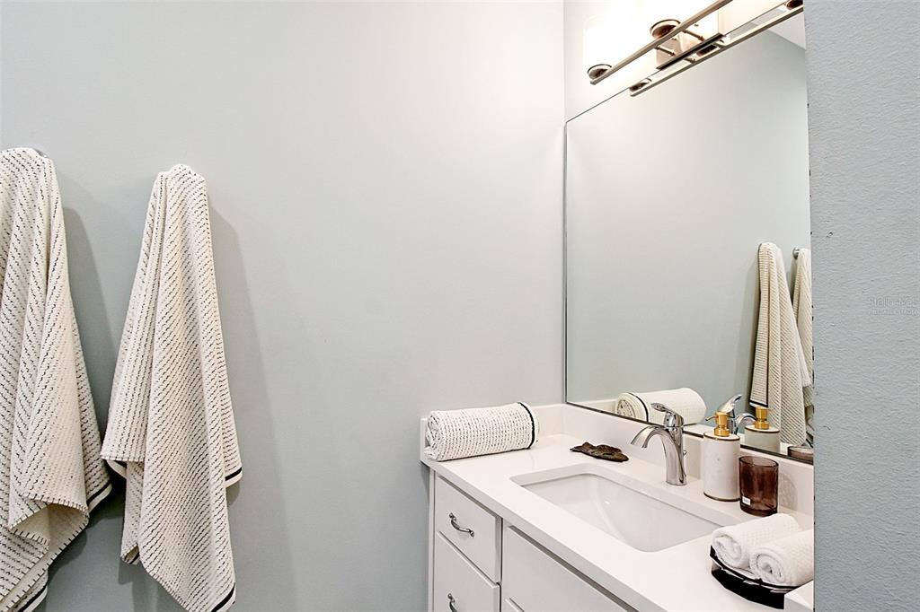 A bathroom features a white vanity with a sink, a large mirror, and hanging towels — 14550 SCHOFIELD ROAD UNIT 3, PORT CHARLOTTE, FL