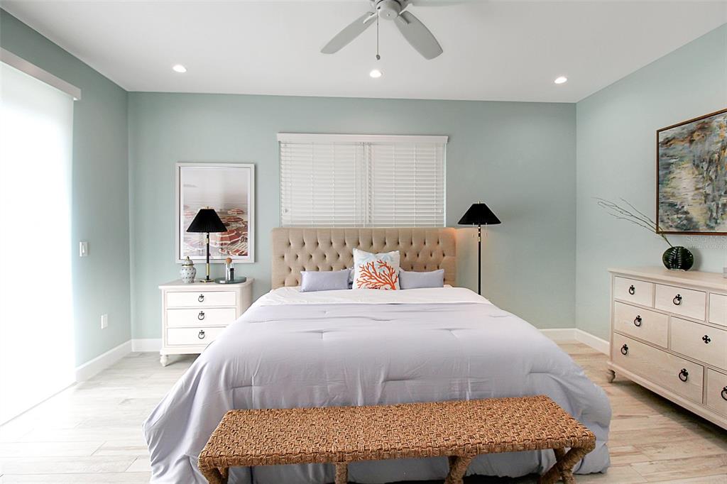 A bedroom features a tufted headboard, light blue walls, a ceiling fan, and wooden furniture — 14550 SCHOFIELD ROAD UNIT 3, PORT CHARLOTTE, FL