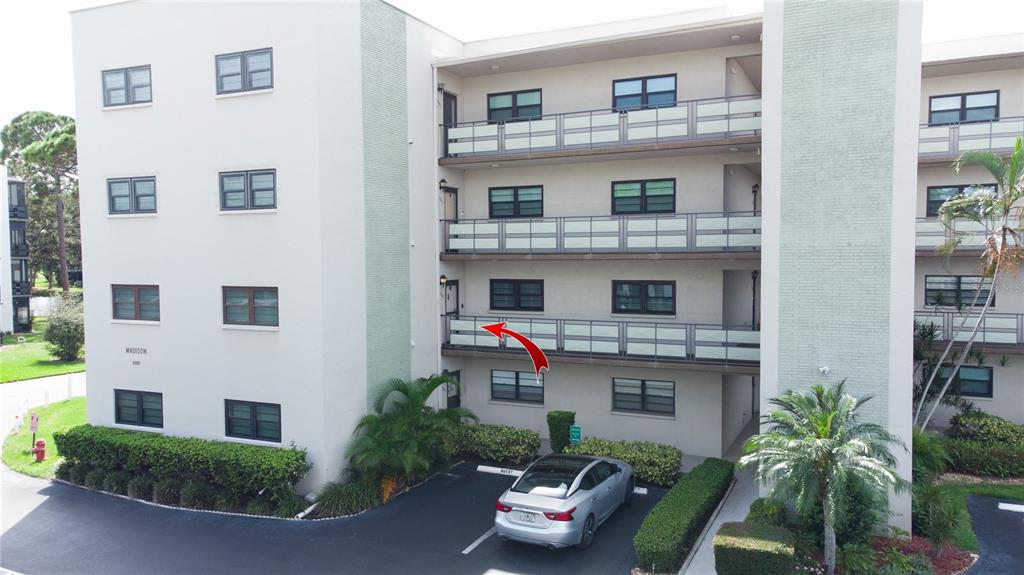 An exterior view of a multi-story apartment building with a red arrow pointing toward a balcony — 6080 80TH STREET N UNIT 201, ST PETERSBURG, FL