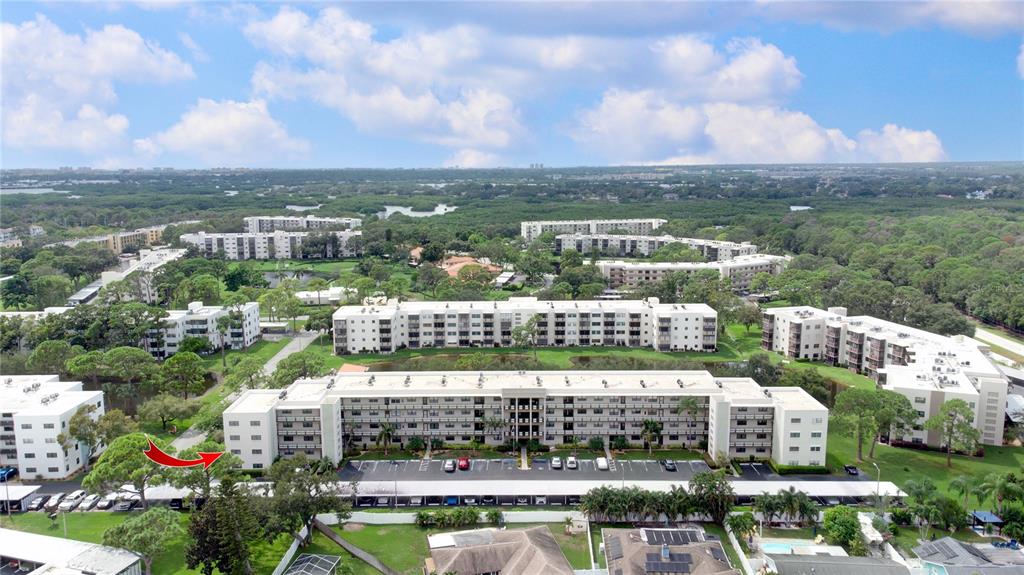 An aerial view shows several multi-story apartment buildings surrounded by trees and parking lots — 6080 80TH STREET N UNIT 201, ST PETERSBURG, FL