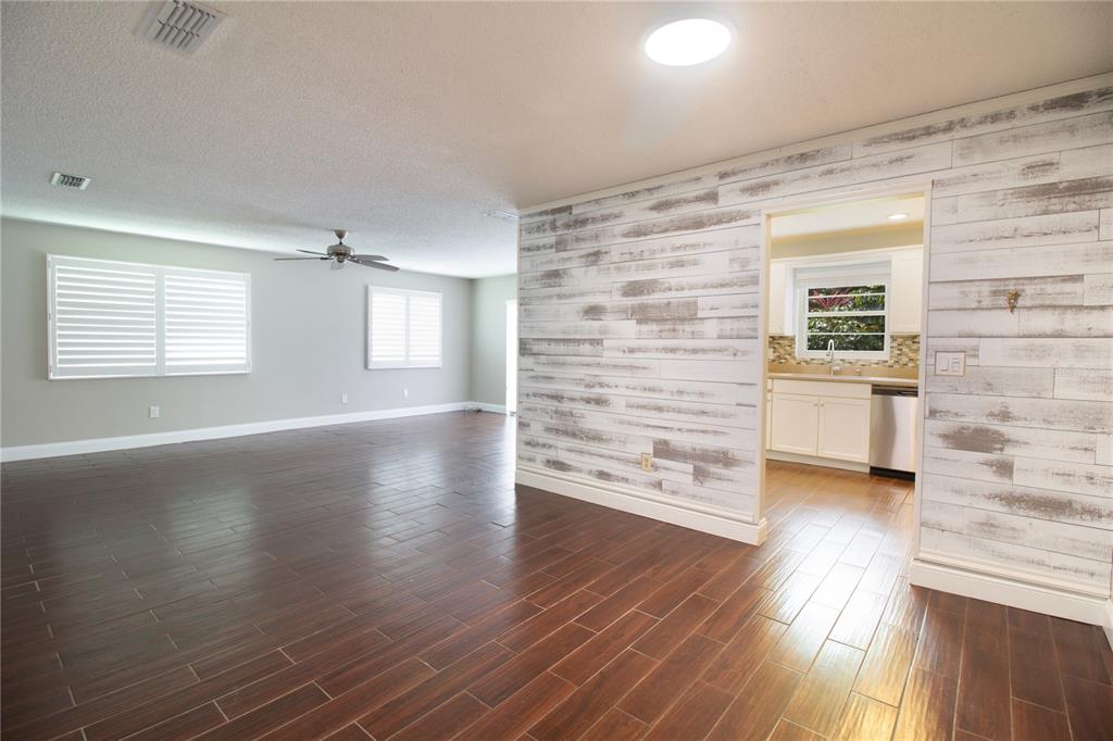 A living room with dark wood-look tile floors features a rustic white shiplap accent wall — 6080 80TH STREET N UNIT 201, ST PETERSBURG, FL