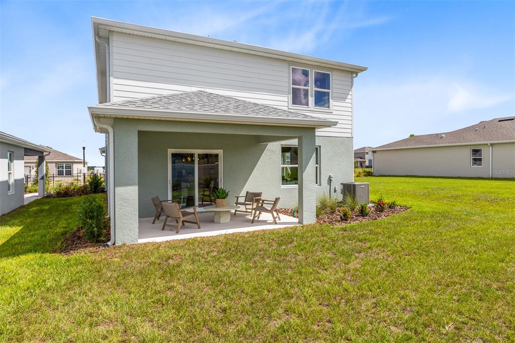 A covered patio with outdoor furniture sits behind a two-story house with a grassy yard — 3741 HADDON AVE, DAVENPORT, FL