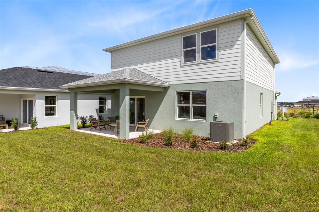 The exterior of a two-story house features a covered patio, siding, and a grassy yard — 3741 HADDON AVE, DAVENPORT, FL