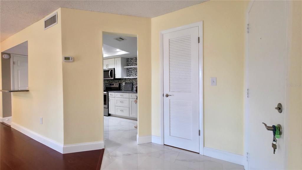 A view from a hallway looking into a kitchen with white cabinets and tile floors — 2025 SYLVESTER ROAD UNIT N109, LAKELAND, FL