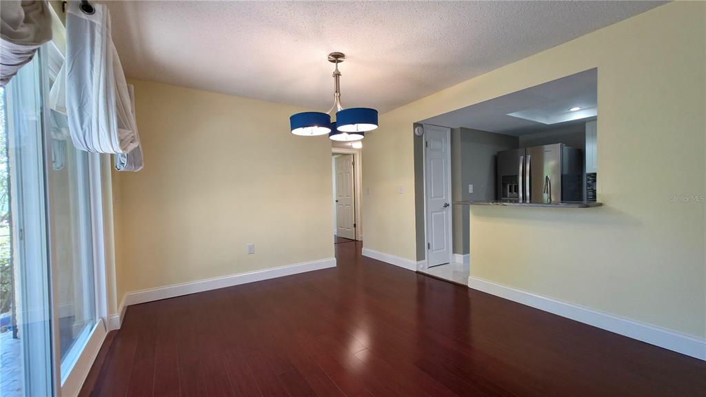 A dining room with dark wood floors, yellow walls, and a blue three-light chandelier — 2025 SYLVESTER ROAD UNIT N109, LAKELAND, FL
