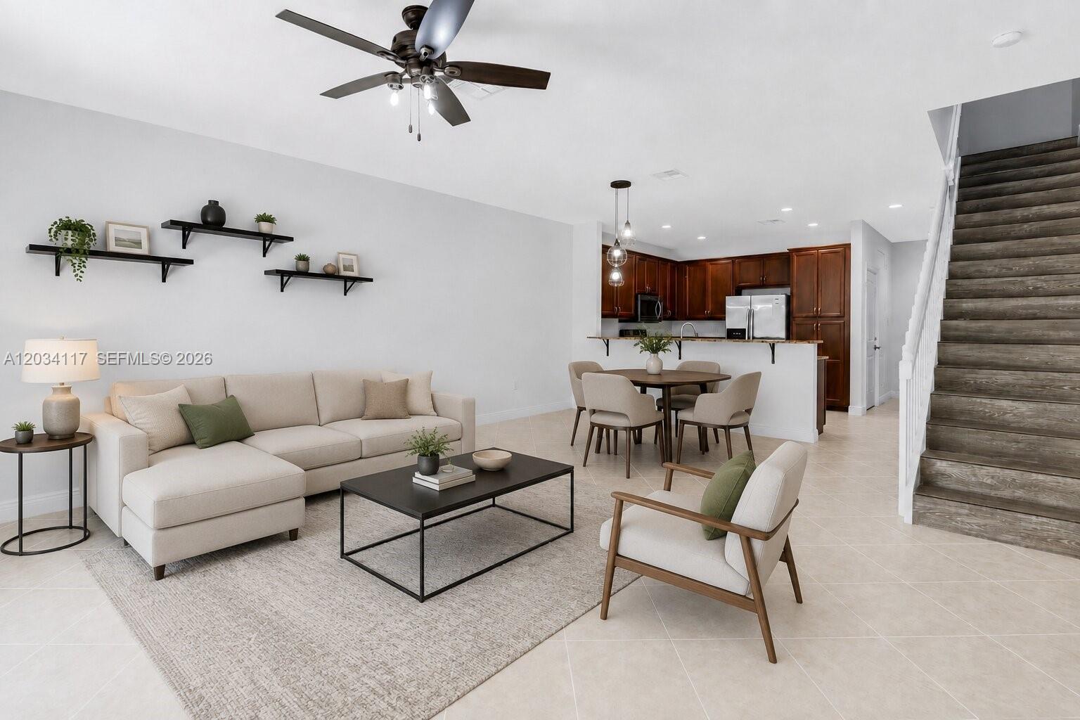 An open-concept living and dining area features a sectional sofa, wooden staircase, and kitchen — 7782 Paddock Pl, Davie FL 33328, DAVIE, FL