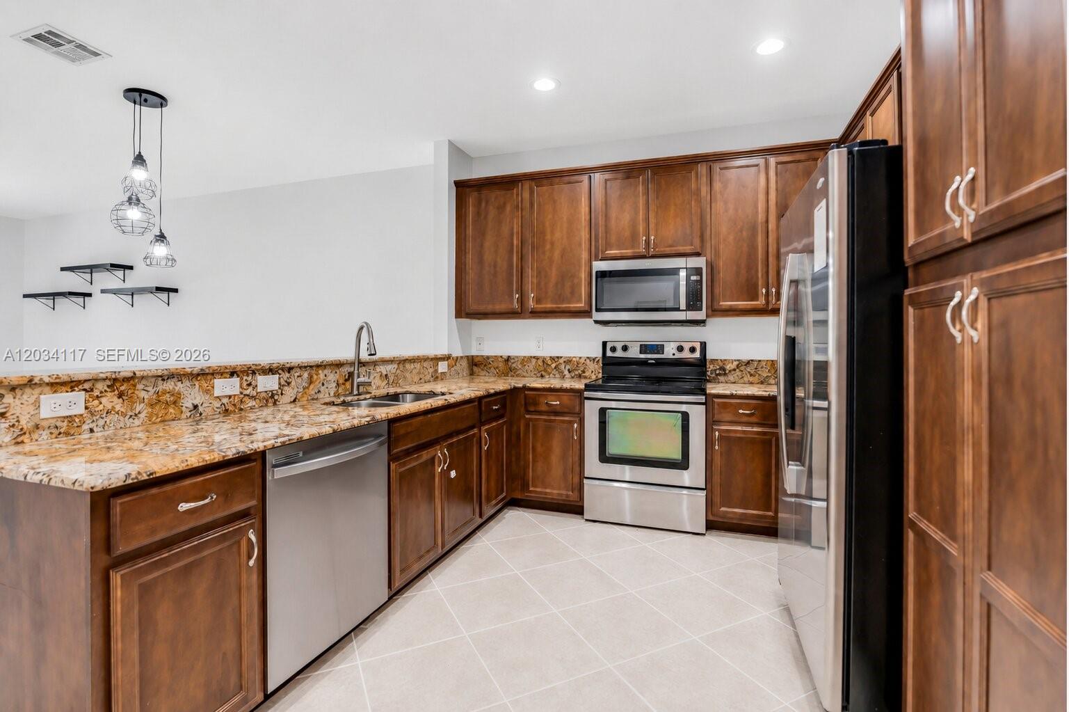 A kitchen features dark wood cabinets, granite countertops, and stainless steel appliances — 7782 Paddock Pl, Davie FL 33328, DAVIE, FL