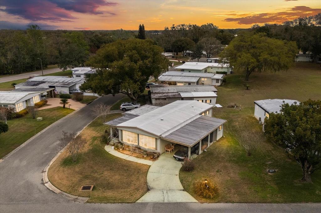 A single-story house with a front porch, large windows, and a carport at sunset — 2129 OAK GROVE DRIVE UNIT 58, ZELLWOOD, FL