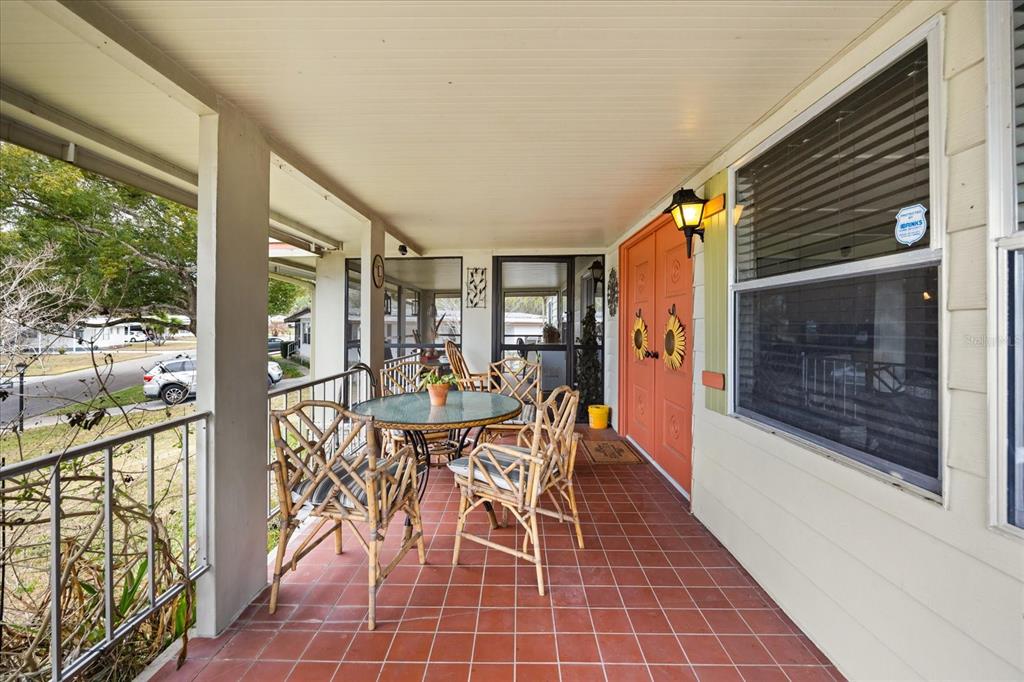 A covered patio features red tile flooring, a glass-top table with chairs, and orange doors — 2129 OAK GROVE DRIVE UNIT 58, ZELLWOOD, FL