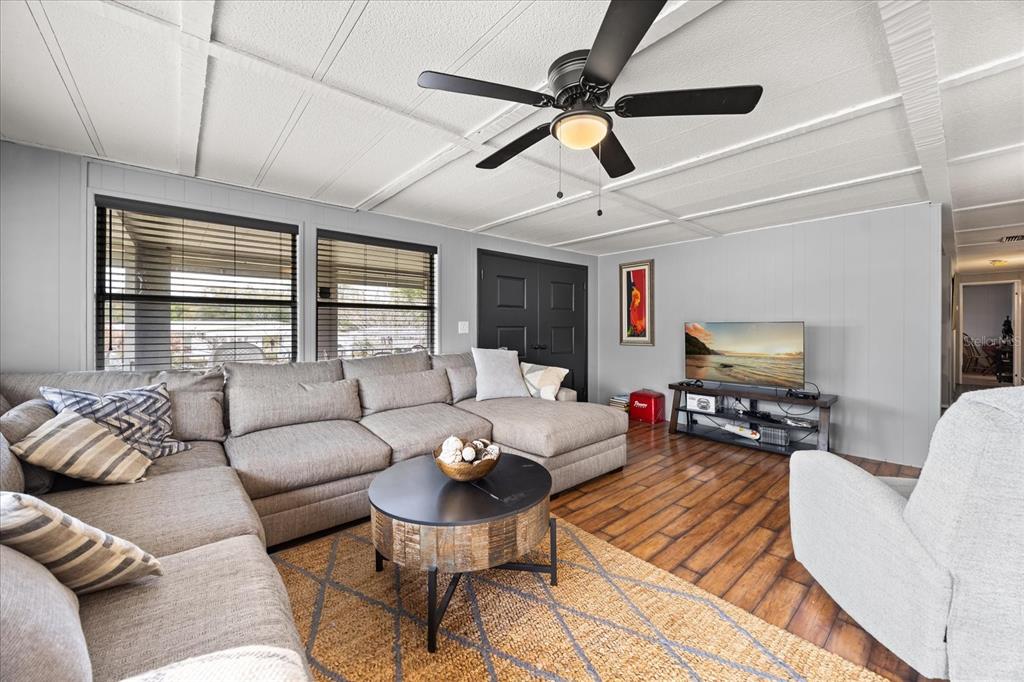A living room features a gray sectional sofa, a round coffee table, and a ceiling fan — 2129 OAK GROVE DRIVE UNIT 58, ZELLWOOD, FL