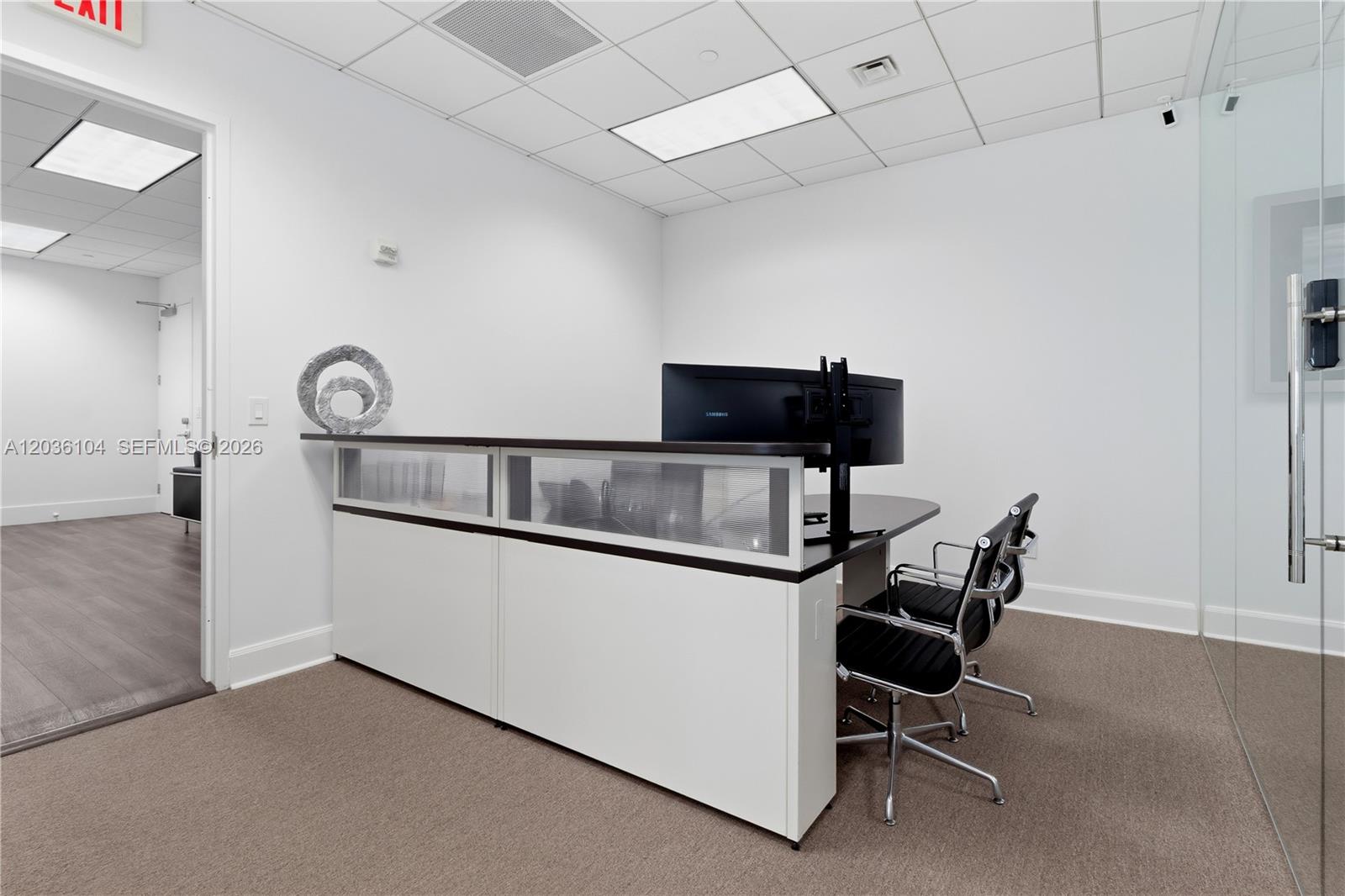 An office space features a reception desk, two black chairs, and a glass wall partition — 175 SW 7th St # 1612, Miami FL 33130, MIAMI, FL