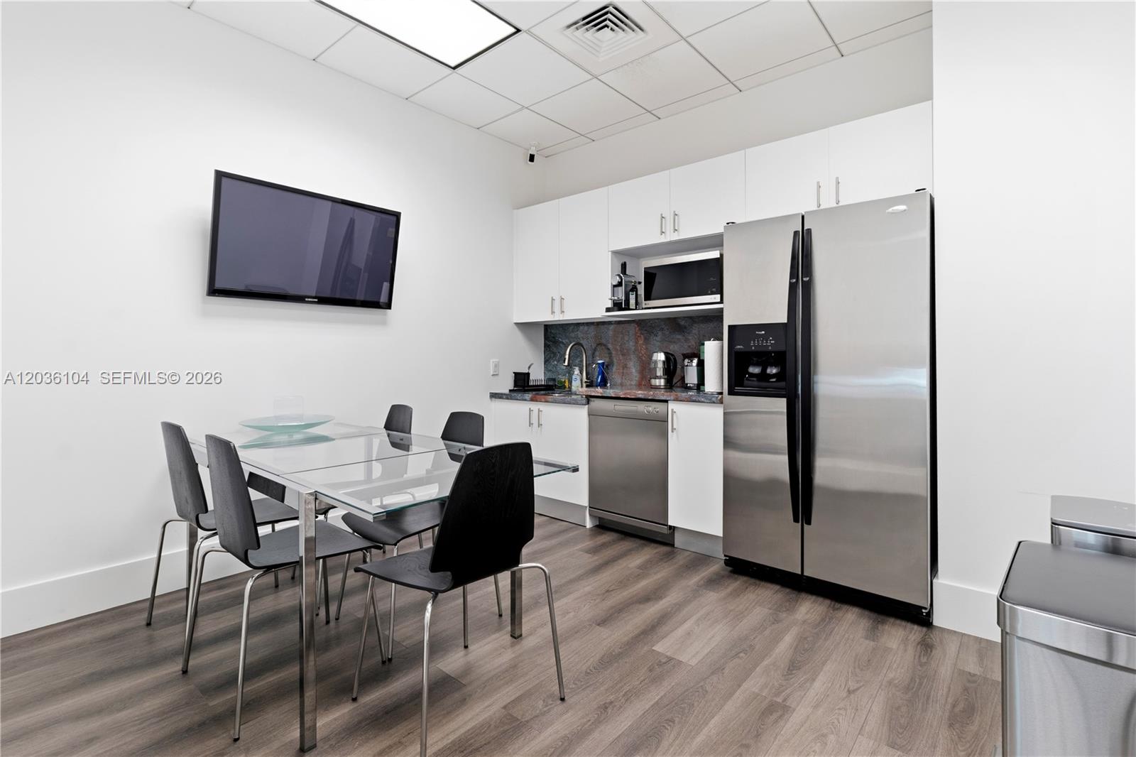 A modern kitchen and dining area features white cabinets, stainless steel appliances, and a glass table — 175 SW 7th St # 1612, Miami FL 33130, MIAMI, FL
