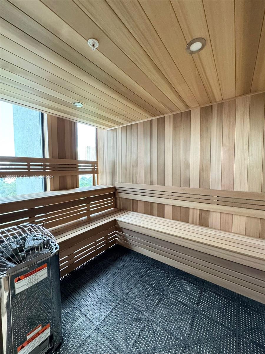 A sauna room features wood-paneled walls, tiered benches, a heater with rocks, and a window — 1642 NE 1st Ave # 2203, Miami FL 33132, MIAMI, FL