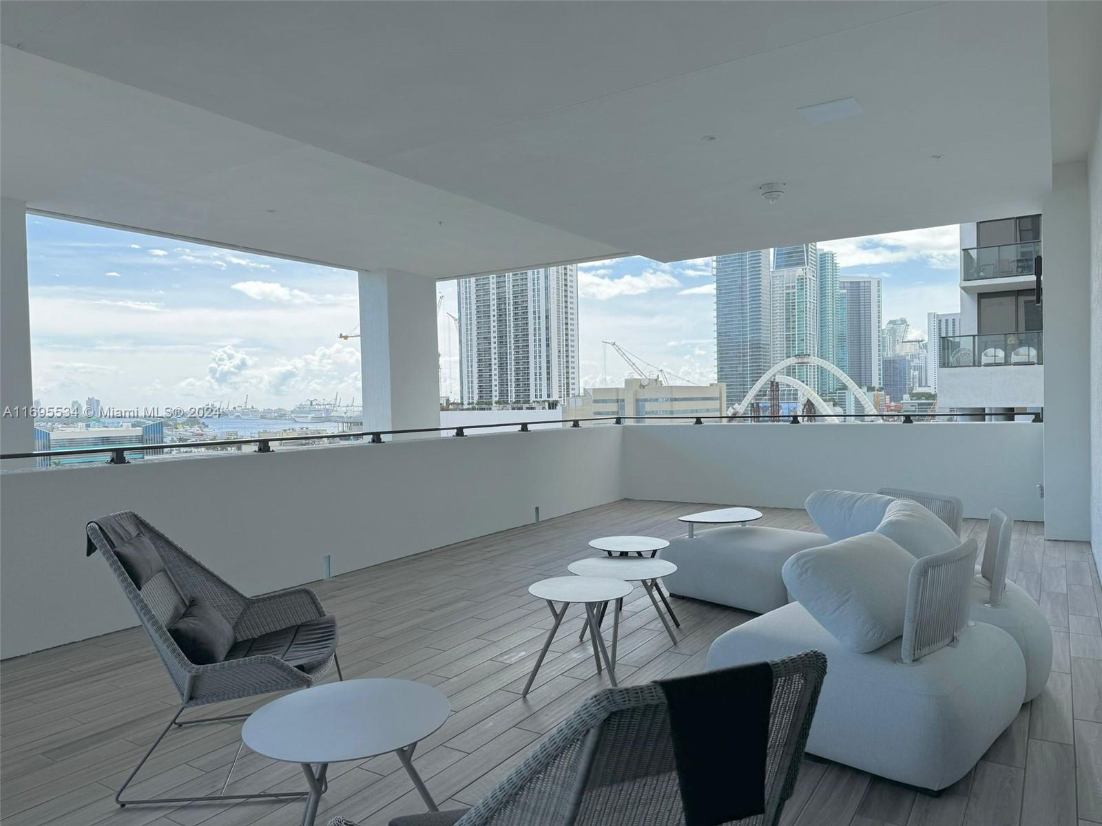 A spacious covered balcony features modern outdoor furniture, wood-look tile flooring, and city skyline views — 1642 NE 1st Ave # 2203, Miami FL 33132, MIAMI, FL