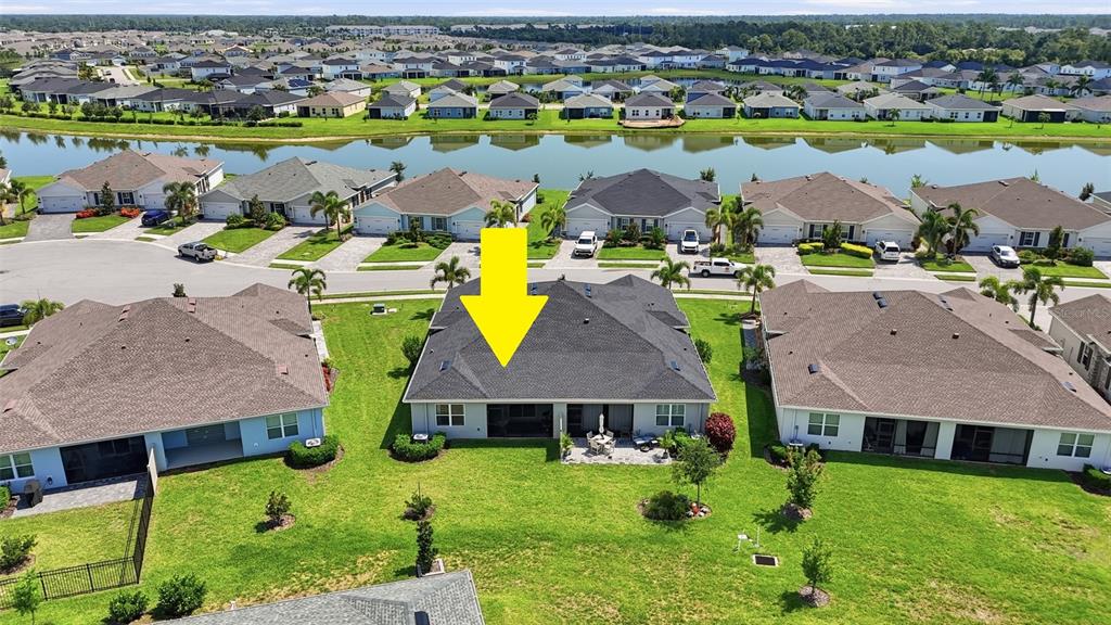 An aerial view shows the rear exterior of a suburban house with a yellow arrow — 16300 COCONUT PALM DRIVE, PORT CHARLOTTE, FL