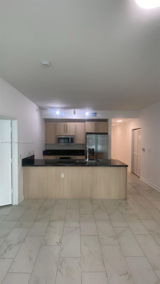 A kitchen features light wood cabinets, black countertops, and a central island with tile flooring — 1111 SW 1st Ave, Miami FL 33130, MIAMI, FL