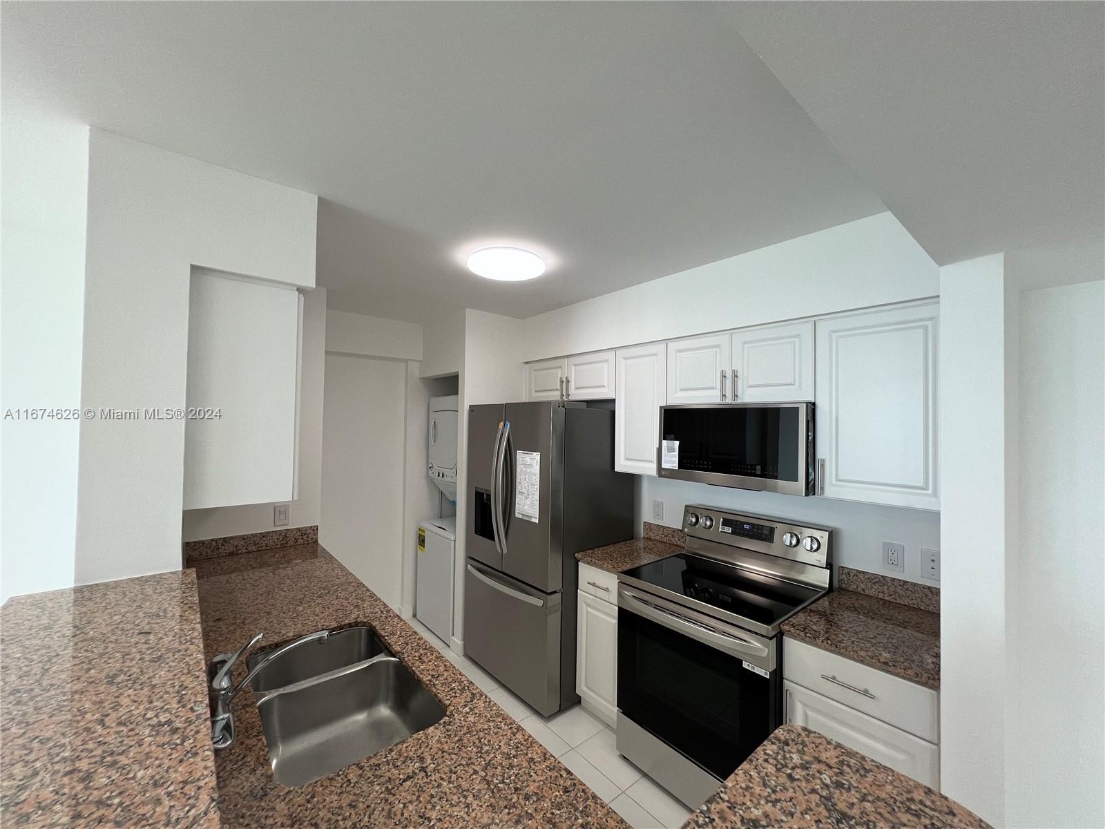 A kitchen features white cabinets, granite countertops, stainless steel appliances, and an adjacent laundry closet — 1155 Brickell Bay Dr # 3205, Miami FL 33131, MIAMI, FL