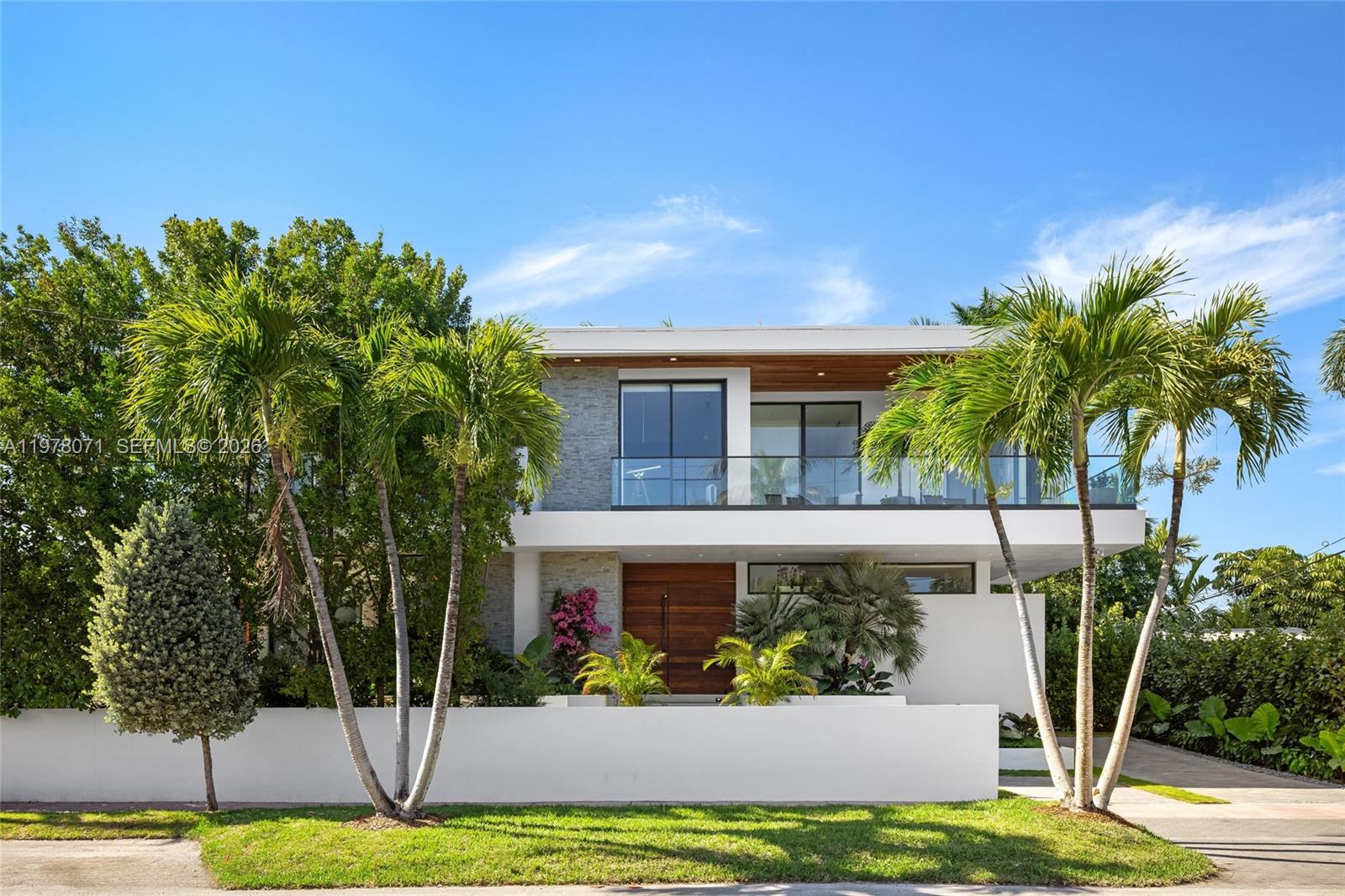 A modern two-story house features a flat roof, stone accents, and a glass-railed balcony — 5701 N Bay Rd, Miami Beach FL 33140, MIAMI BEACH, FL