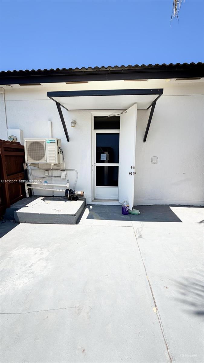 An exterior view shows a white wall with an open door, an air conditioning unit, and a concrete patio — 18405 SW 132nd Ave # 18405, Miami FL 33177, MIAMI, FL