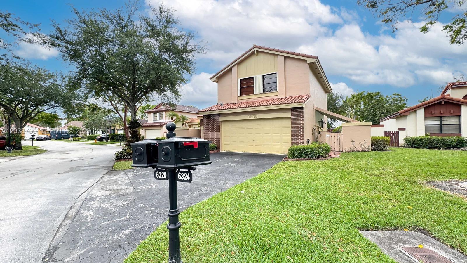 A two-story suburban house with a tan stucco exterior, a garage, and a shared mailbox — 6320 NW 173rd St, Hialeah FL 33015, HIALEAH, FL