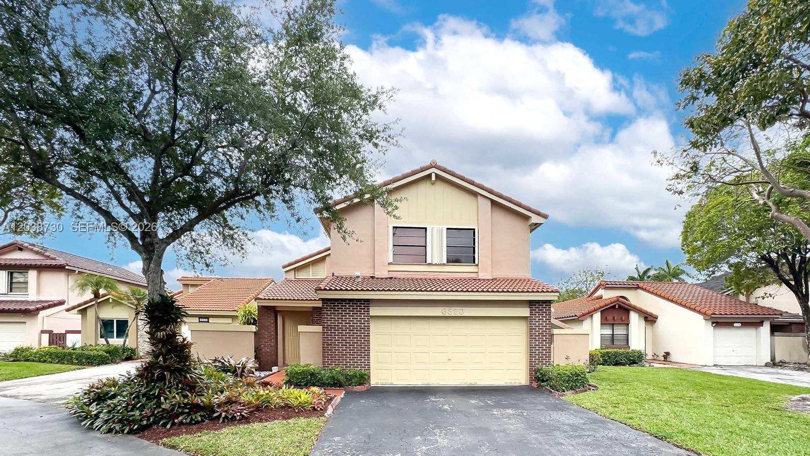A two-story house with a beige stucco exterior, brick accents, and a tiled roof — 6320 NW 173rd St, Hialeah FL 33015, HIALEAH, FL