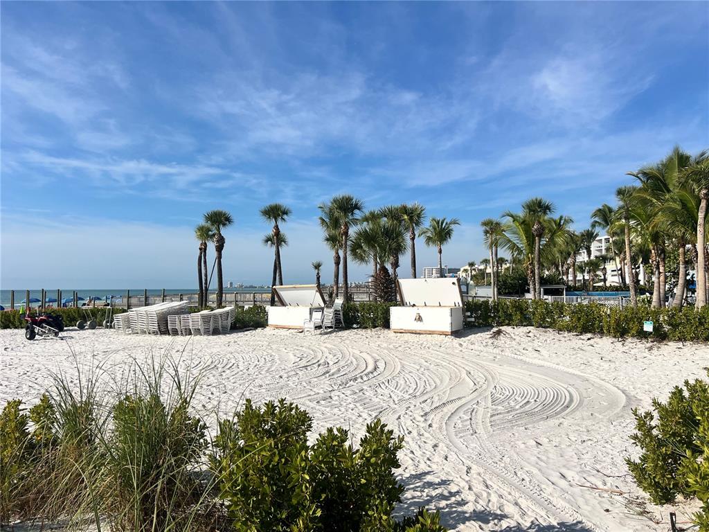 A sandy beach area features palm trees, white storage bins, and rows of stacked lounge chairs — 1001 POINT OF ROCKS ROAD UNIT 309, SARASOTA, FL