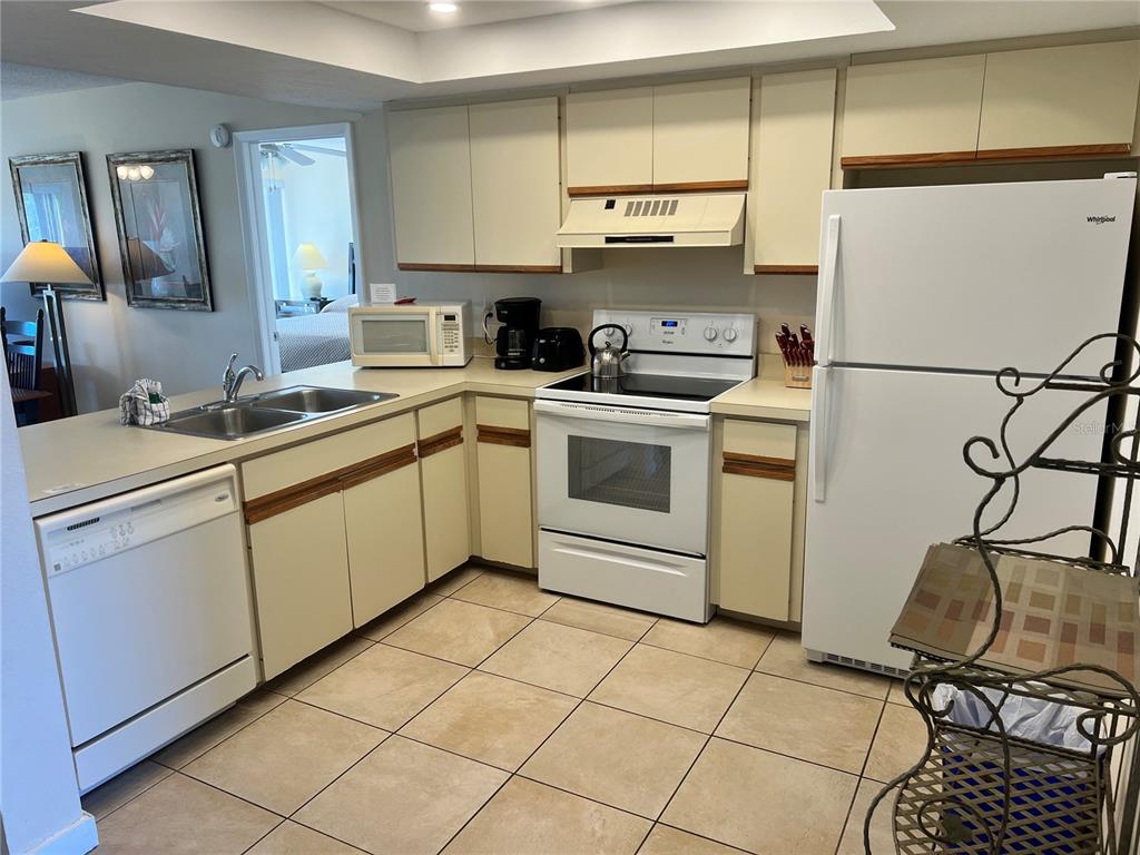 A kitchen with white appliances, light-colored cabinets, tile flooring, and a double sink — 1001 POINT OF ROCKS ROAD UNIT 309, SARASOTA, FL