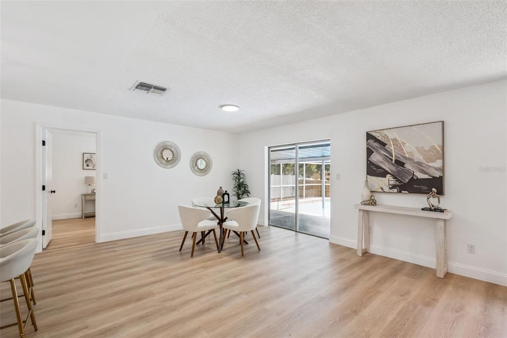 A dining area with light wood flooring, a glass table, and sliding glass patio doors — 336 TANGERINE STREET, ALTAMONTE SPRINGS, FL