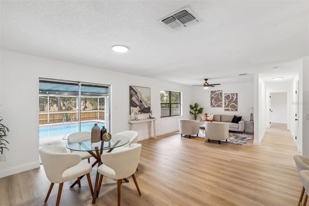 A bright open-concept living and dining area features light wood floors and a backyard pool — 336 TANGERINE STREET, ALTAMONTE SPRINGS, FL