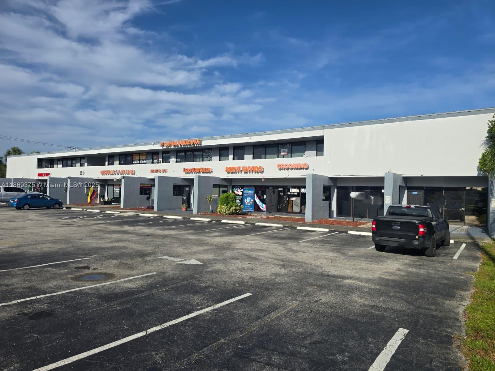 A two-story commercial strip mall features multiple storefronts with a large asphalt parking lot — 2501 N State Road 7, Margate FL 33063, MARGATE, FL