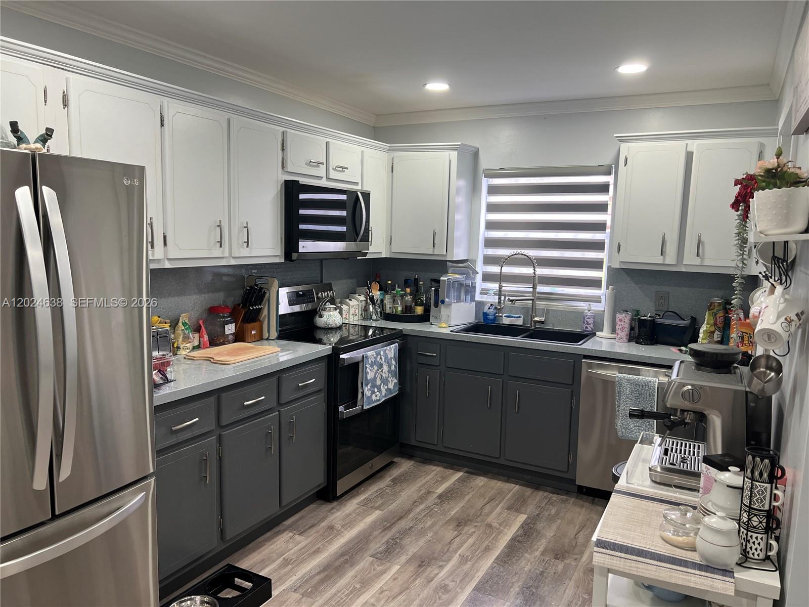 A kitchen features two-toned white and dark gray cabinetry, stainless steel appliances, and wood-look flooring — 5300 Washington St # H140, Hollywood FL 33021, HOLLYWOOD, FL