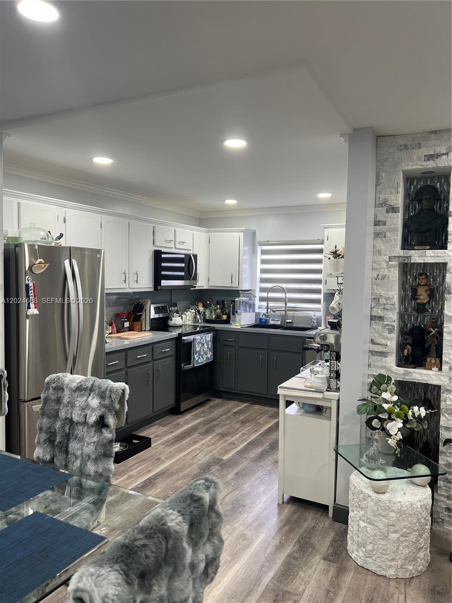 A kitchen features two-toned cabinetry, stainless steel appliances, and a stone-accented wall with niches — 5300 Washington St # H140, Hollywood FL 33021, HOLLYWOOD, FL