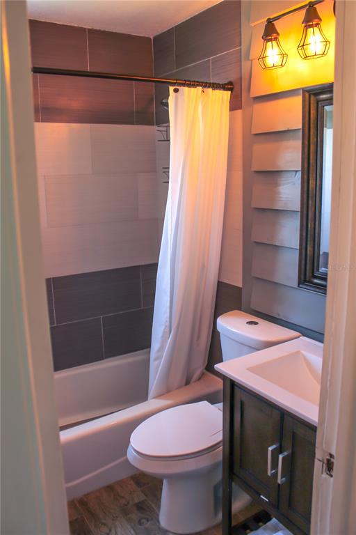 A bathroom features a tiled shower, a white toilet, and a dark wood vanity — 4457 FLORAMAR TERRACE, NEW PORT RICHEY, FL