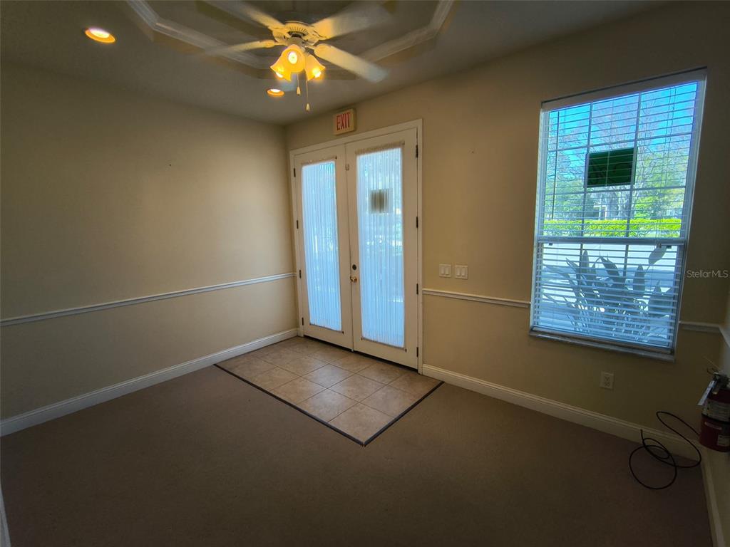 A room with beige walls, carpeted flooring, a tiled entryway, and double glass doors — 4875 PALM COAST PARKWAY NW UNIT 4, PALM COAST, FL