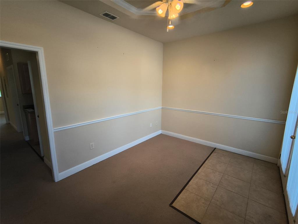An empty room features beige carpet, a tiled entry area, and white chair rail molding — 4875 PALM COAST PARKWAY NW UNIT 4, PALM COAST, FL