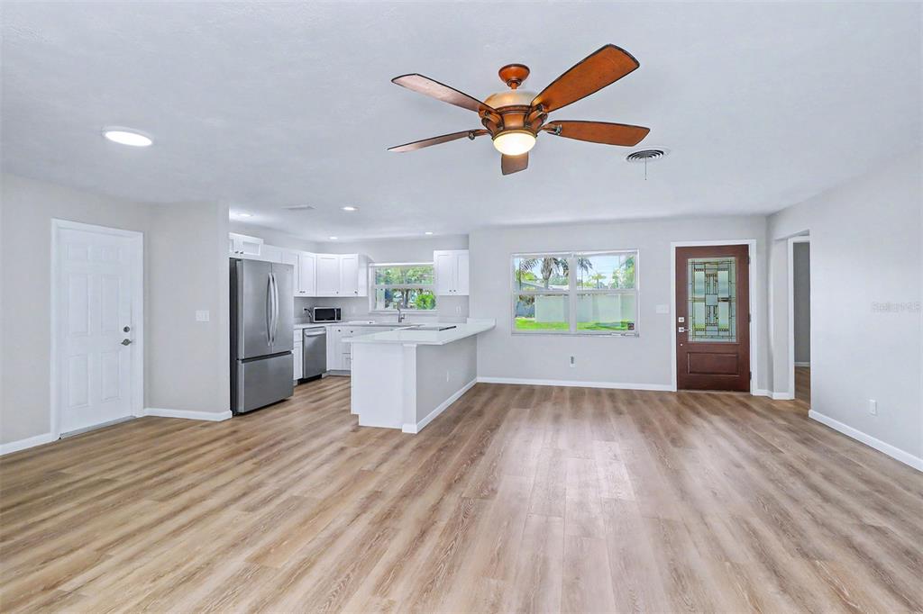 An open-concept kitchen and living area features light wood-look flooring, white cabinetry, and stainless appliances — 7901 3RD STREET N, ST PETERSBURG, FL