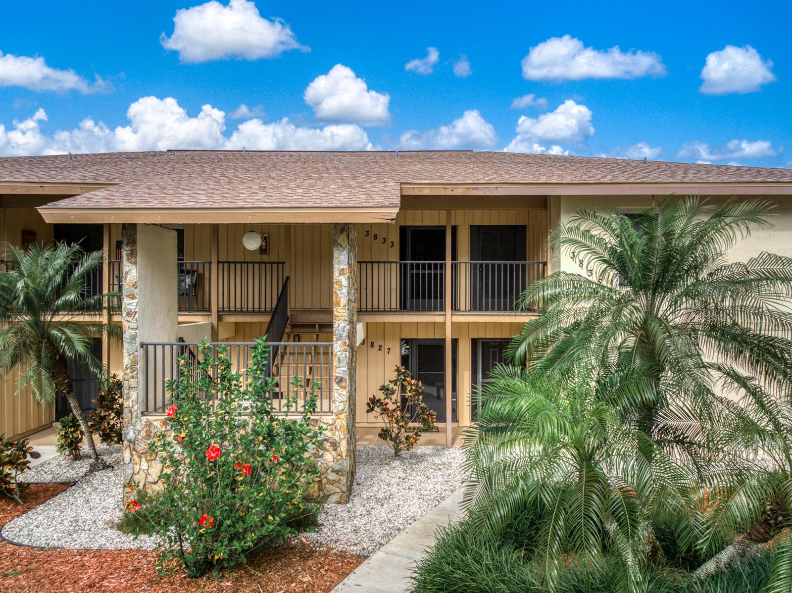 A two-story apartment building exterior features stone pillars, metal railings, and tropical landscaping — 3833 Edgewater Drive, Sebring FL 33872, SEBRING, FL