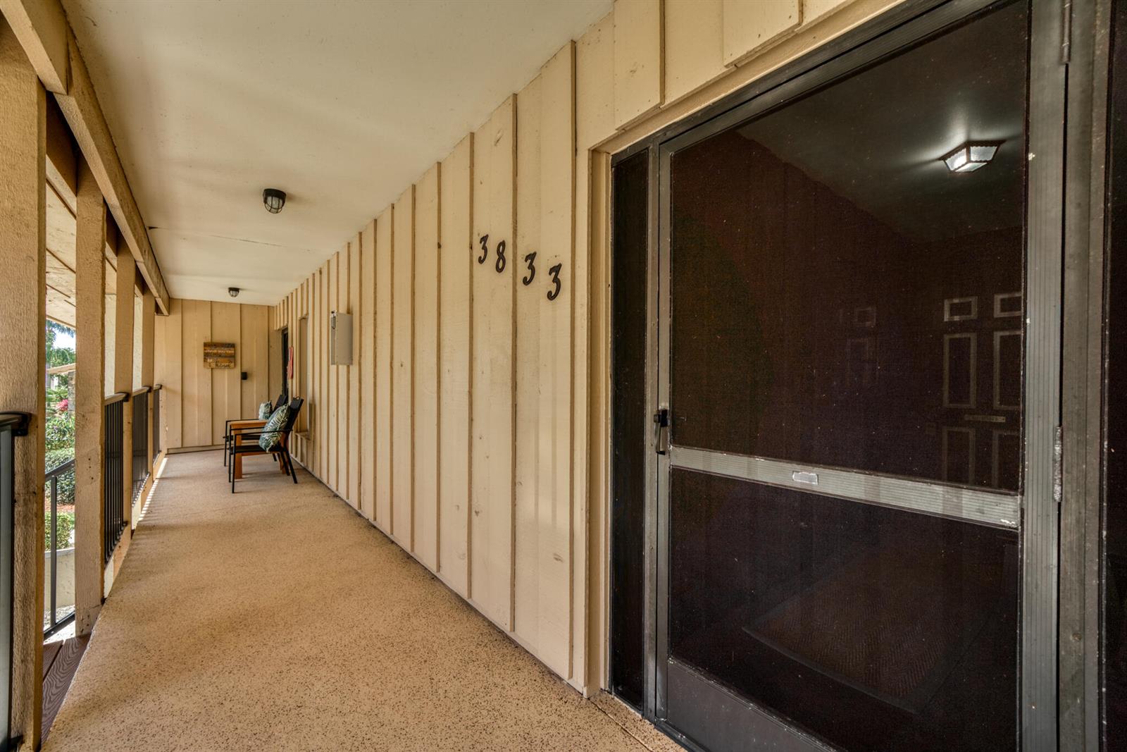 An outdoor walkway features tan vertical siding, a screen door, and a small seating area — 3833 Edgewater Drive, Sebring FL 33872, SEBRING, FL