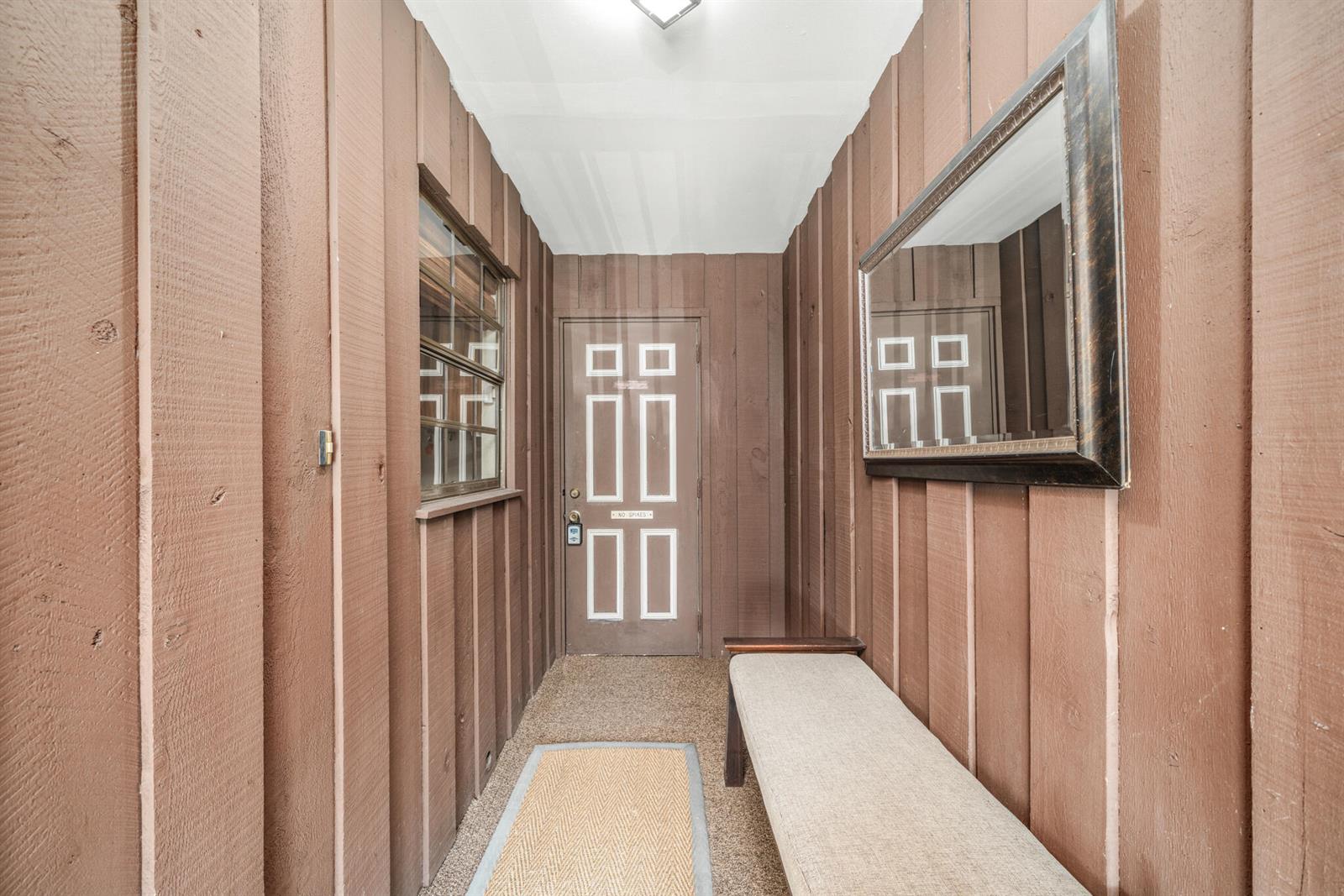 A narrow entryway features brown vertical wood paneling, a bench, a mirror, and a door — 3833 Edgewater Drive, Sebring FL 33872, SEBRING, FL