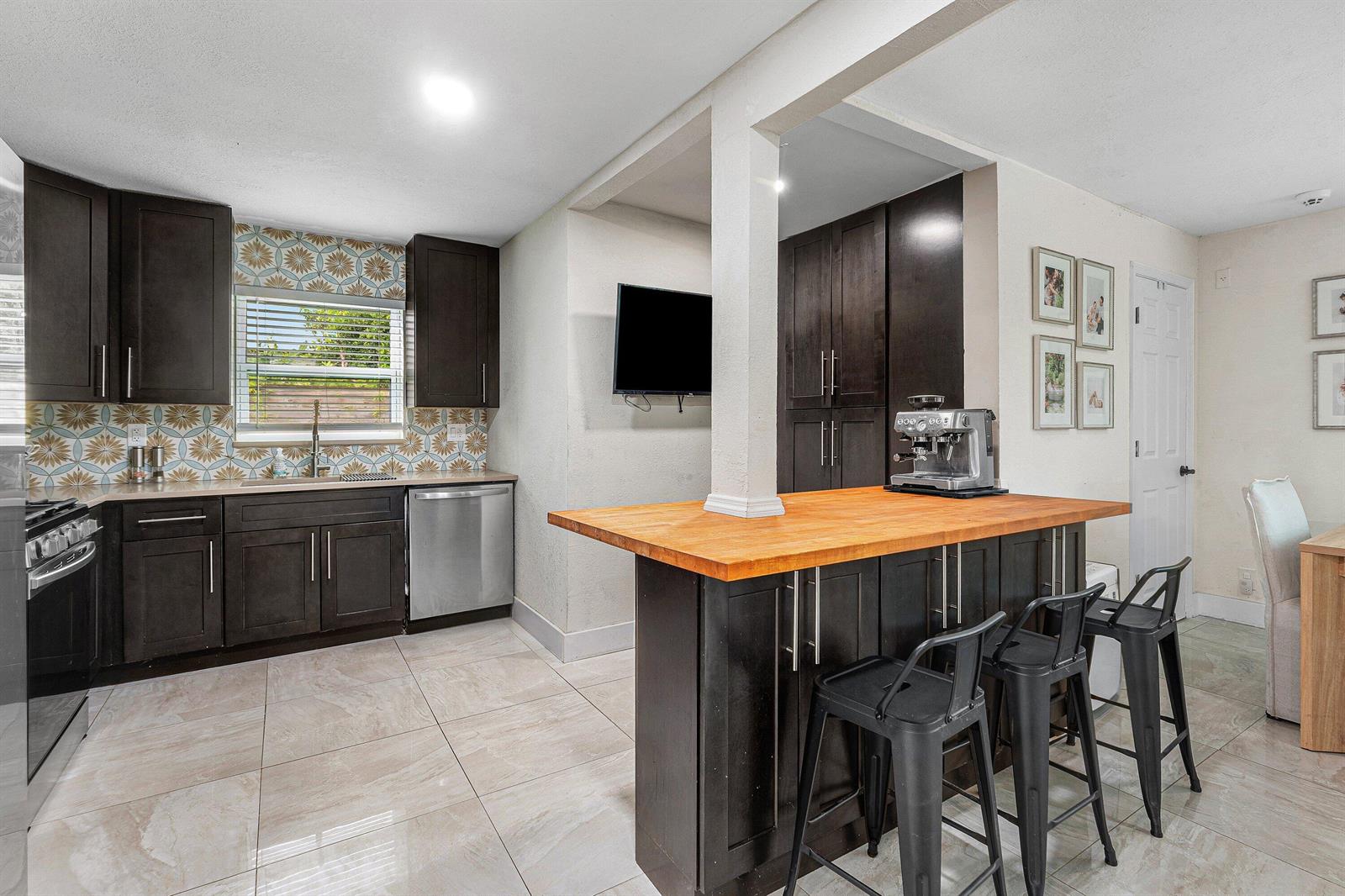 A kitchen features dark wood cabinets, a butcher block island, and patterned tile backsplashes — 711 Laurel Drive, Lake Park FL 33403, LAKE PARK, FL