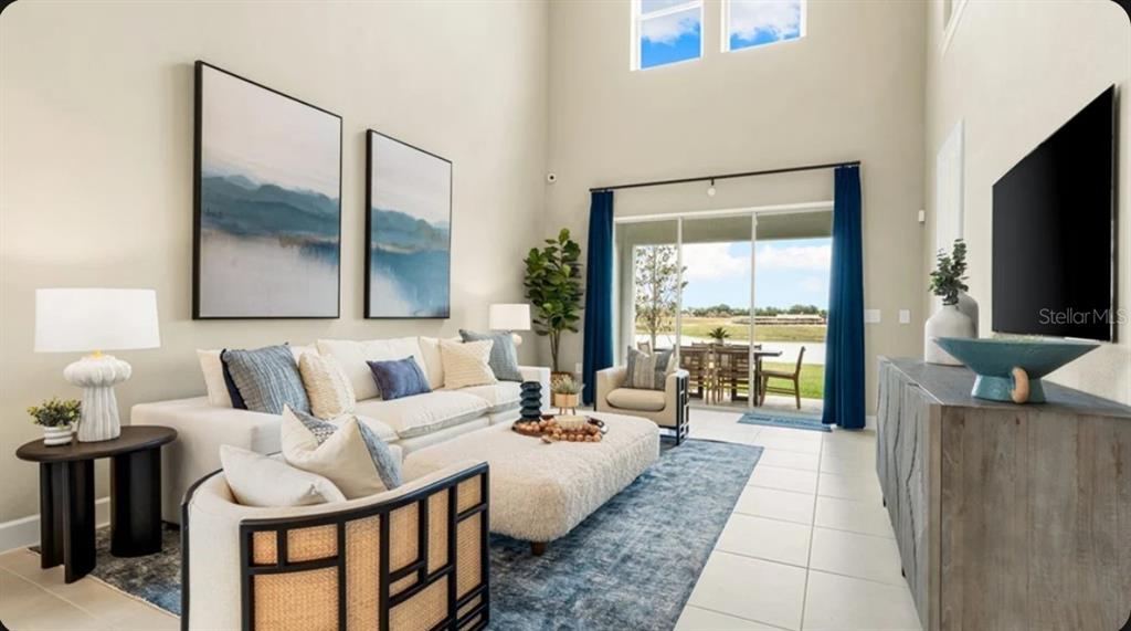 A living room with high ceilings, a large sofa, a television, and sliding glass doors — 823 STEEL DRIVE, APOLLO BEACH, FL