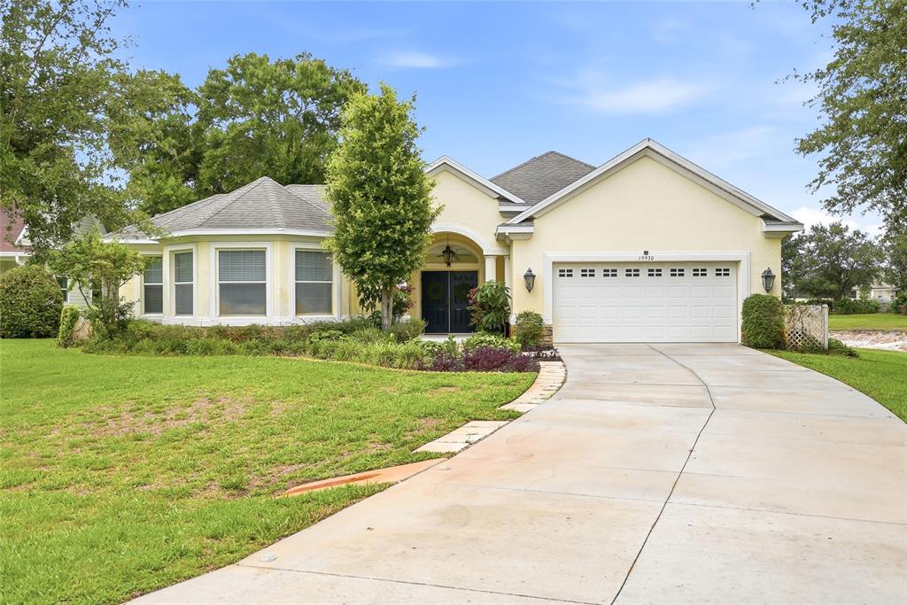 A single-story house with a yellow exterior, a two-car garage, and a concrete driveway — 19930 DOLORES ANN COURT, LUTZ, FL