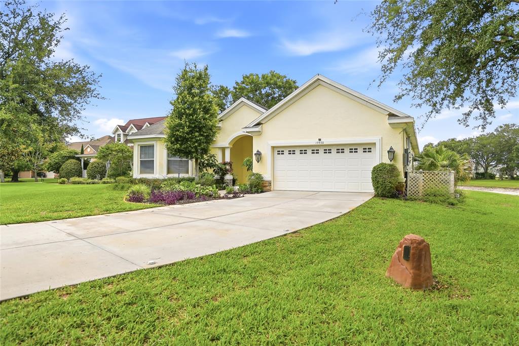 A single-story yellow house with a two-car garage and a concrete driveway — 19930 DOLORES ANN COURT, LUTZ, FL