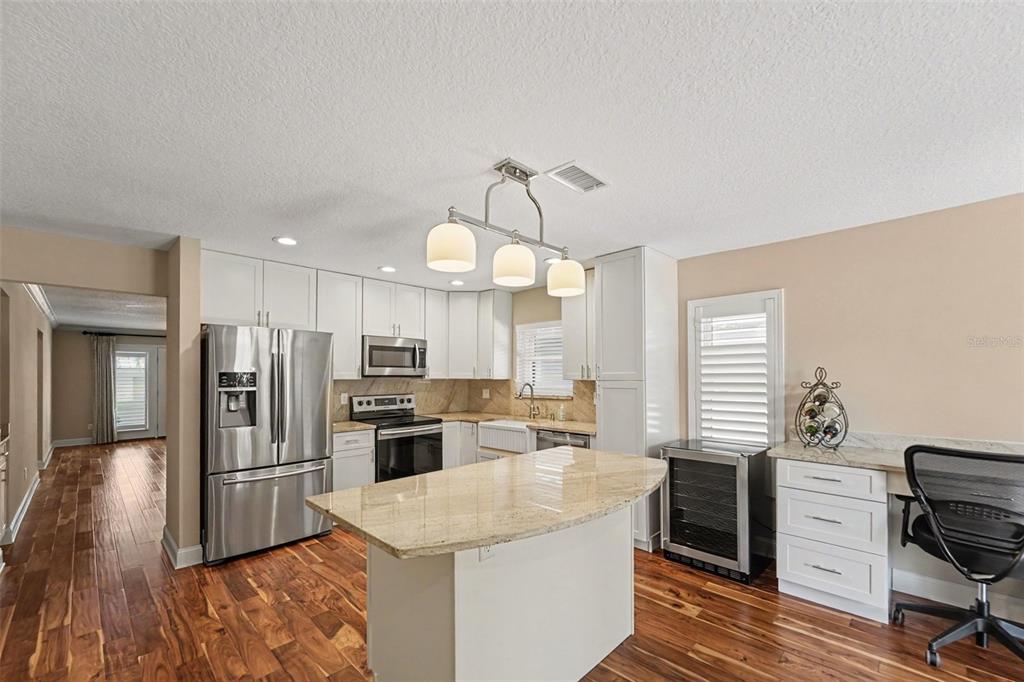 A kitchen features white cabinetry, stainless steel appliances, a granite island, and wood flooring — 1683 WATERMARK CIRCLE NE, ST PETERSBURG, FL