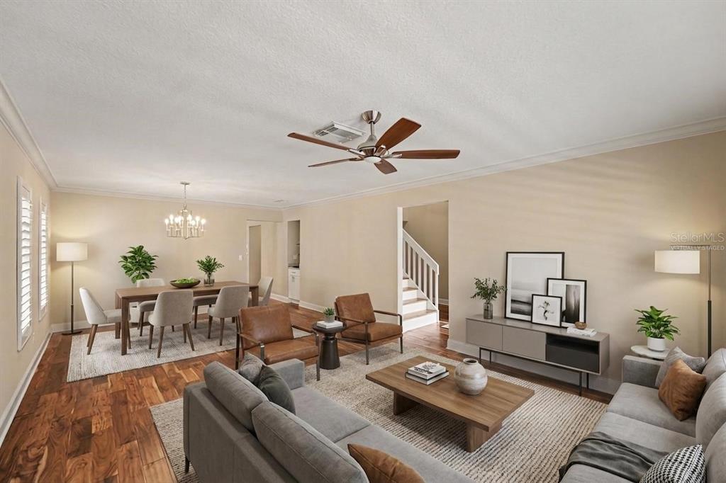 This is a virtually staged living and dining room with hardwood floors and a ceiling fan — 1683 WATERMARK CIRCLE NE, ST PETERSBURG, FL