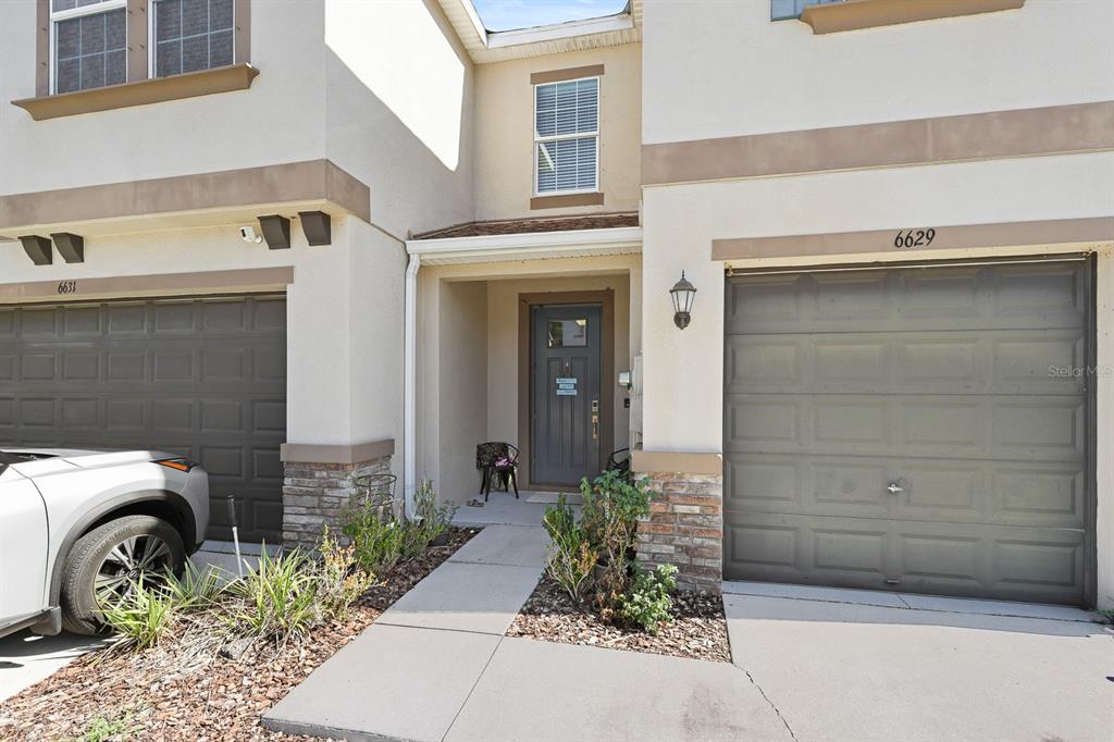 The exterior of a two-story townhouse features two garage doors, a recessed entryway, and stone accents — 6629 ROCKY PARK STREET, TAMPA, FL