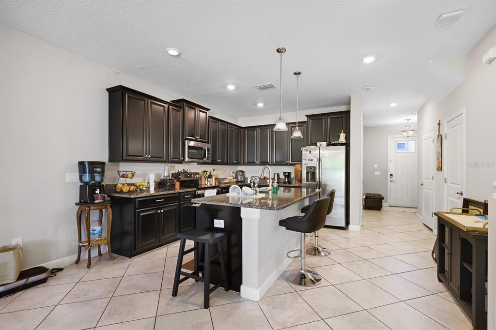 A kitchen features dark wood cabinets, granite countertops, a center island, and tile flooring — 6629 ROCKY PARK STREET, TAMPA, FL