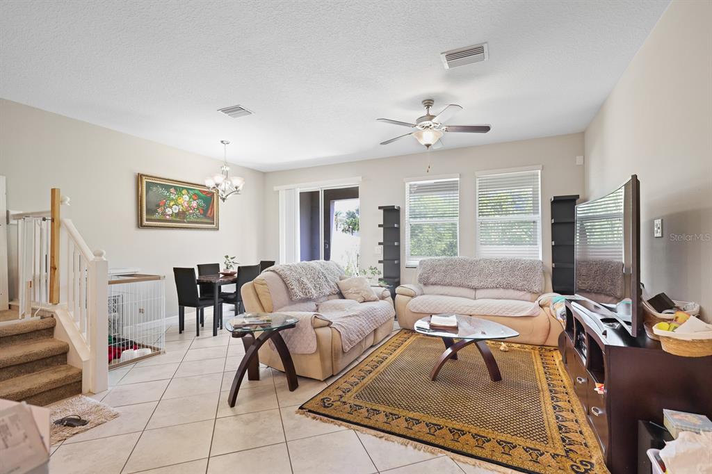A living room and dining area with tile floors, beige sofas, and a ceiling fan — 6629 ROCKY PARK STREET, TAMPA, FL